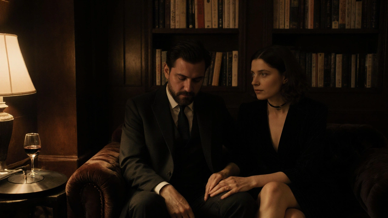 A man and woman sitting together on a velvet sofa in soft light, sharing a silent, emotional moment.